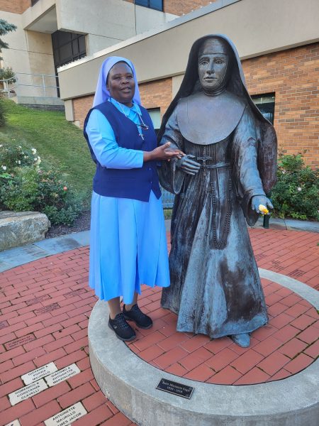 Sister Mary Grace taking a picture with statue of St. Marianne Cope in Syracuse
